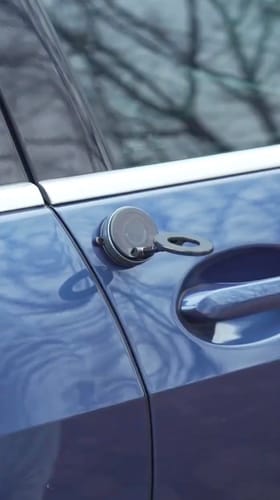 Reviewer testing the MagPro Magnetic Phone Holder's powerful grip on the side of a blue car door.