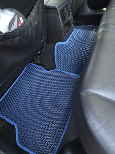Recenzent pokazuje dopasowane, niebieskie dywaniki samochodowe na podłodze z tyłu pojazdu.