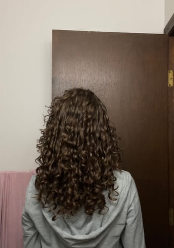 Reviewer from behind showing defined, shiny curls after using the SET Gel-To-Foam Styling Mousse.