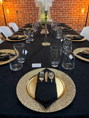 Customer's elegant party table set for the 1920s Murder Mystery Game, with gold chargers and a character name card.