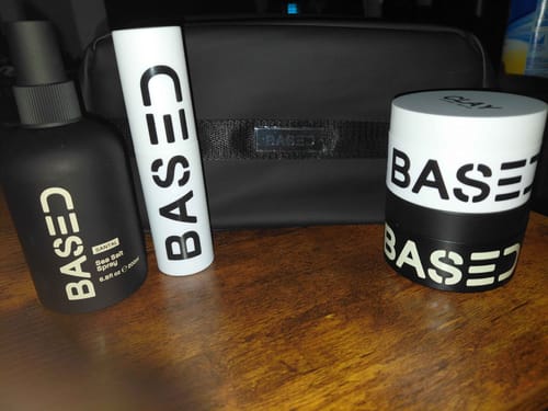 Reviewer's black Toiletry Bag sitting on a wooden table behind several hair products.