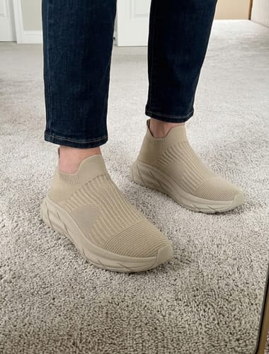 Reviewer wearing the beige, sock-style Ortho Slip shoes with dark jeans indoors.