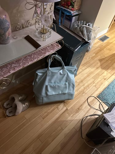 Reviewer's light blue Weekender Bag sitting on a wood floor in a room.