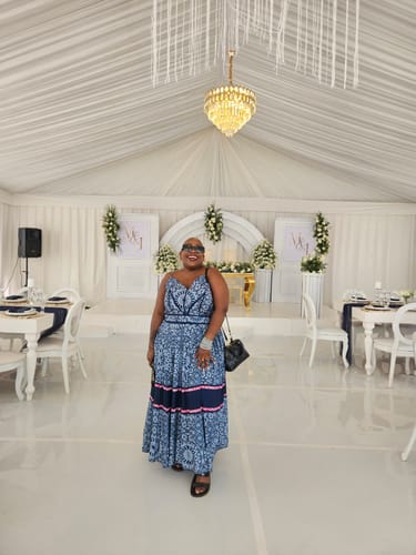 Customer smiling while wearing the blue patterned African Ankara Pleated Midi Dress at an indoor event.