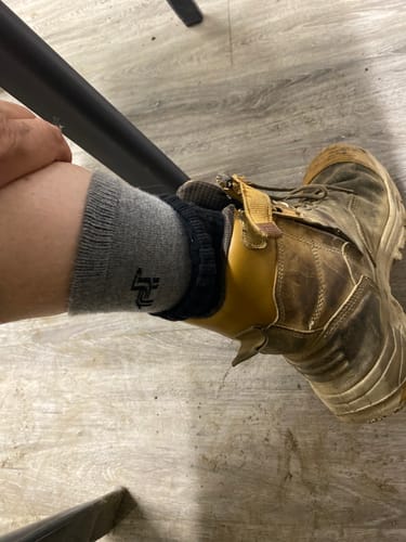 Reviewer showing grey Crew Socks worn as an inner layer under a thicker sock with a rugged work boot.