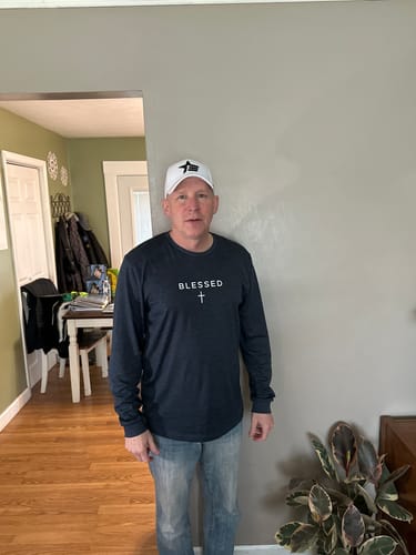 Customer wearing the white Rogue Snapback hat with a black logo while standing indoors.
