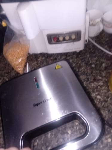 Partial view of the customer's silver electric sandwich grill, closed and sitting on a kitchen counter.