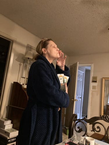 Reviewer in a robe smoking a Blue Dream Pre Roll while holding several packs of the product.