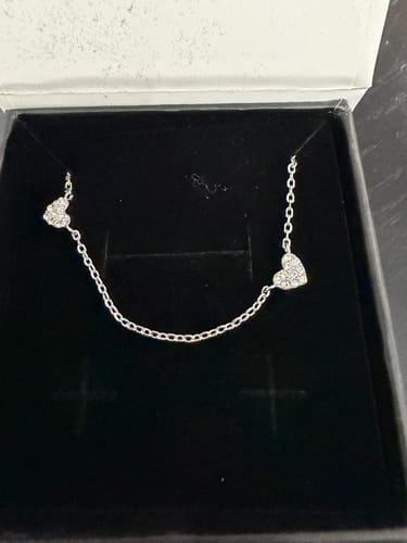 Reviewer's Irene Heart Station Necklace with sparkling crystal hearts displayed inside its black-lined gift box.