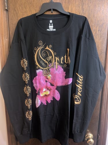Customer's black Opeth - Orchid longsleeve shirt hanging on a door, showing the detailed front graphic and sleeve prints.