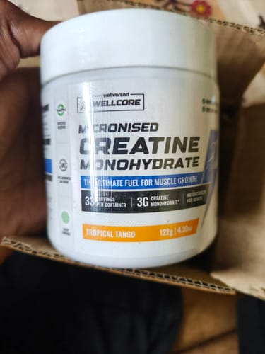 Customer holding the white tub of Wellcore Creatine Monohydrate in the Tropical Tango flavor.