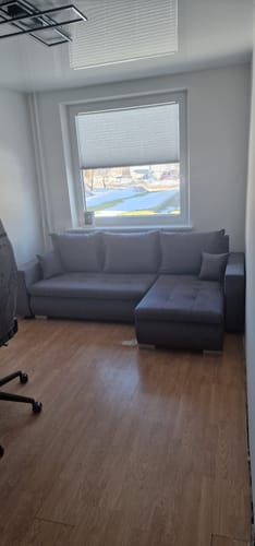 Kliento pilkas minkštas kampas LOKO, pastatytas kambaryje po langu.