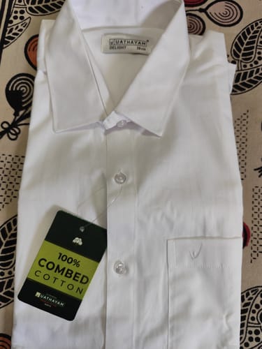 Customer's folded Double Delight white shirt laid flat, showing its collar and 100% combed cotton tag.
