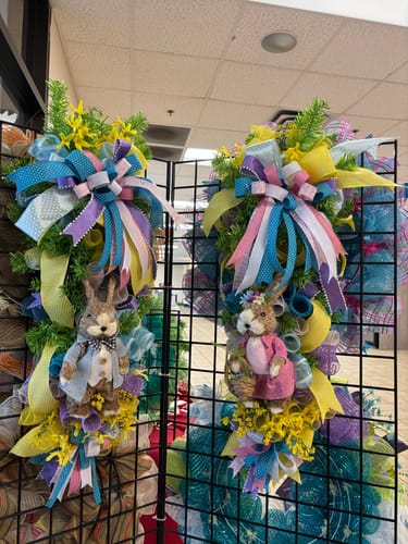 Reviewer showing two handmade wreaths with pastel bows and bunny figures.