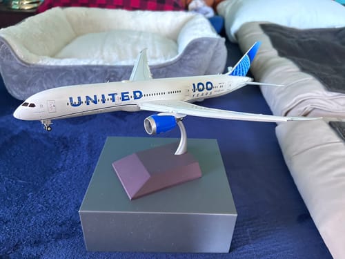 Customer's GEMINI200 UNITED 787-9 model airplane displayed on its stand on a blue surface.