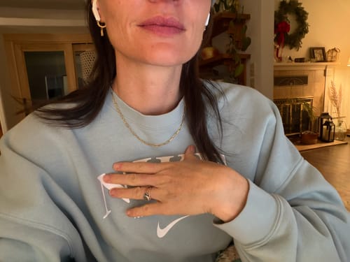 Customer wearing the Maui Paperclip Necklace with a light blue sweatshirt indoors.