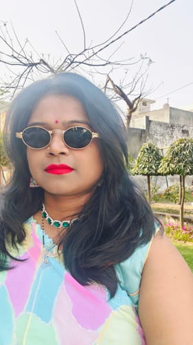 A customer wears the golden oval sunglasses with black lenses outdoors.