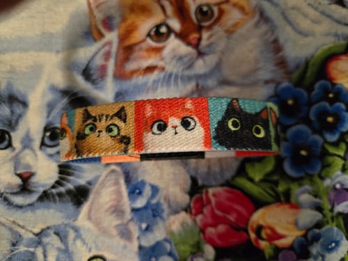 Close-up of a customer's Who Me? Cat Bracelet, showing the colorful cartoon faces of different cats.