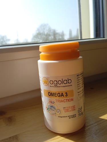 Cliente mostra il flacone di Omega 3 Triaction appoggiato su un davanzale soleggiato.