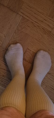 Kundens ben och fötter i de vita Diasocks stödstrumporna, sedda uppifrån.