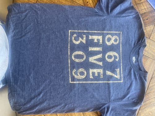 Customer's heather grey 8675309 T-Shirt laid flat, showing the distressed gold print.