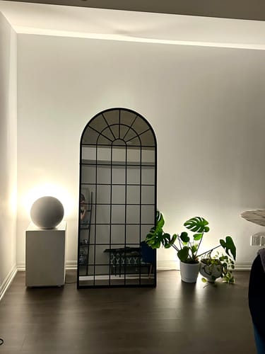 Customer's chic arched mirror with a black frame leaning against a wall in their room.