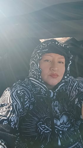 Close-up of a reviewer wearing the Art De La Calle Bandana Hoodie with the hood up in bright sunlight.