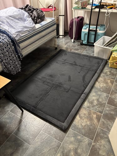 Customer's dark grey Mellow Mat with creases from packaging, expanding on a tiled floor.