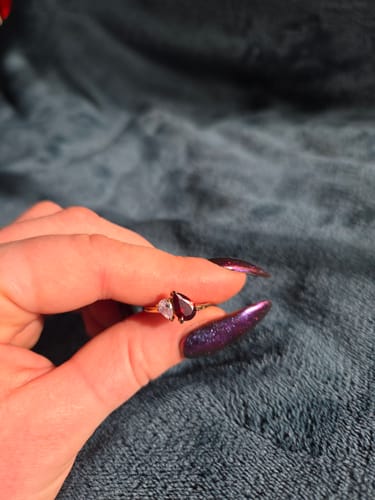 Close-up of a reviewer holding the Leesha Birthstone Ring with two pear-cut stones against a dark background.