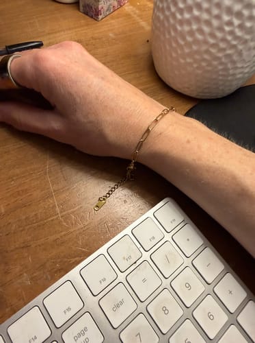 Customer's wrist showing the delicate gold Maui Paperclip Bracelet while working at a desk.