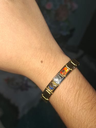 Cliente mostrando la pulsera italiana dorada en la muñeca, con varios charms coloridos de diseño.