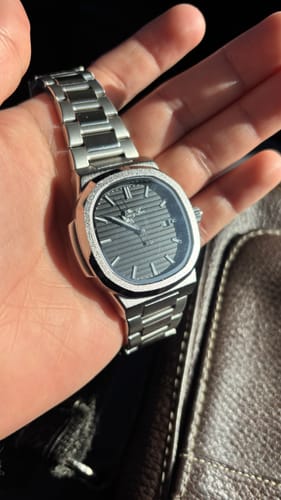 Customer holding the silver Lucky Fours® Caspian watch in their palm, showing the dark, lined face.