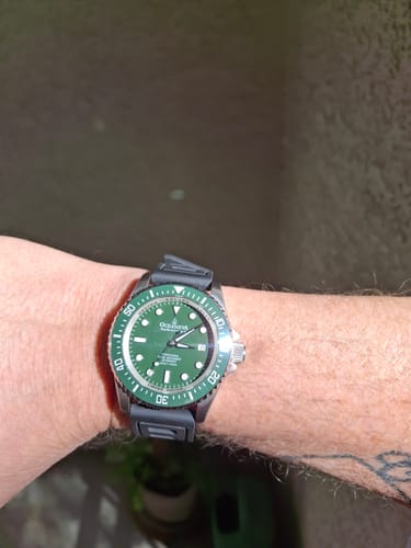 Customer's Oceaneva Deep Marine Explorer II watch with a green dial and bezel, shown on their wrist with a dark strap.