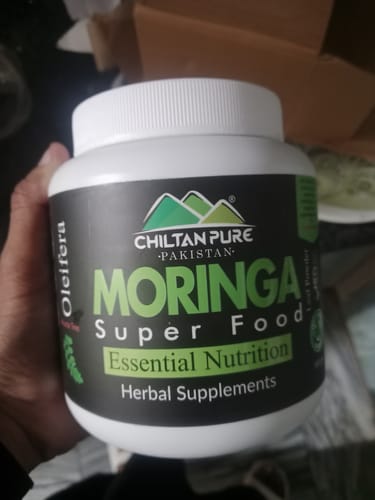 Customer holding a white jar of Chiltan Pure Moringa Super Food.