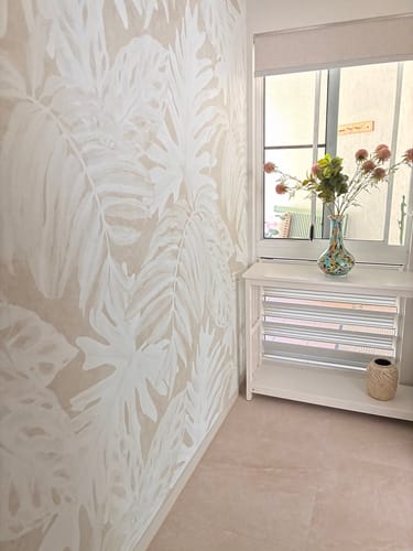 Customer's room showing the White Luxe Palm Wallpaper in Sand installed on a corner wall next to a window.
