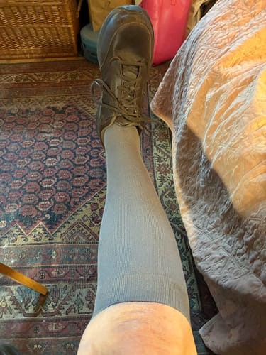 Customer shows the fit of a grey Performance Eucalyptus Compression Sock, covering their leg from foot to knee.