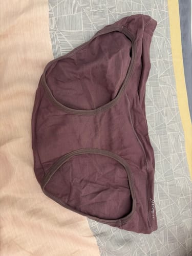 A customer's purple Mère Bottoms laid flat on a patterned bedspread, showing the v-shaped front.