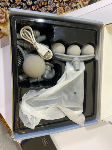 Customer's 9-in-1 Compact Massager in its open box, showing various grey massage heads and a charging cable.