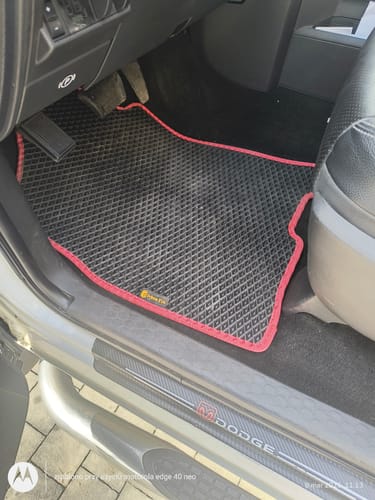 Dywanik samochodowy klienta, czarny z czerwoną lamówką, idealnie dopasowany do podłogi po stronie kierowcy.