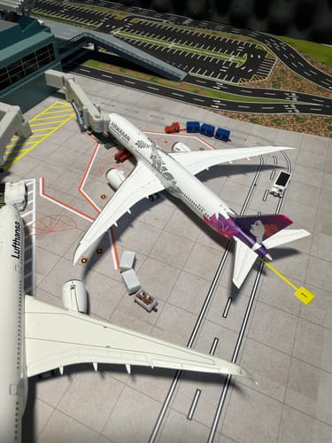 Customer's GEMINI HAWAIIAN 787-9 model plane at a gate on a detailed miniature airport diorama.