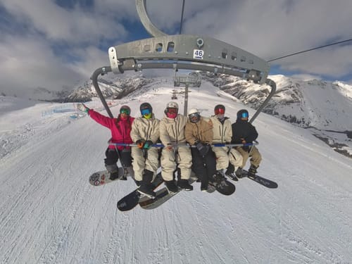 Reviewer and friends on a ski lift, with four people wearing the matching light grey insulated snow jackets.