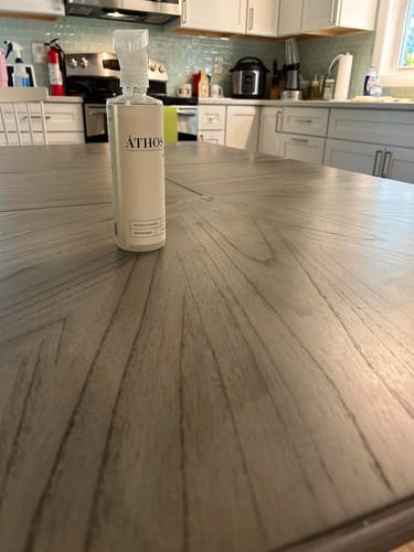 Customer's bottle of Multi-Surface Concentrate on a wood table in a clean kitchen.