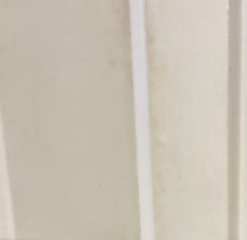 Close-up: Customer's white MEGA Reach Foam Weatherstrip installed vertically in a white door frame.