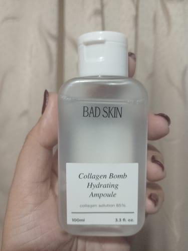 Reviewer holding the translucent bottle of Bad Skin Collagen Bomb Hydrating Ampoule.