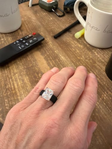 Customer's hand wearing the black silicone ring with its large, emerald-cut CZ stone.