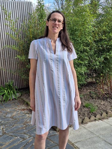 Cliente portant la Robe Céleste à rayures douces, vue de face dans un jardin.