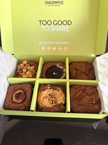 Reviewer's mixed box of six different brownies in a green presentation box. The lid reads 'TOO GOOD TO SHARE'.