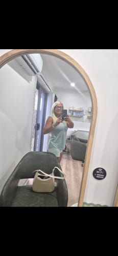 Reviewer takes a mirror selfie, showing their nice tan after using the Intensive Tanning Balm.