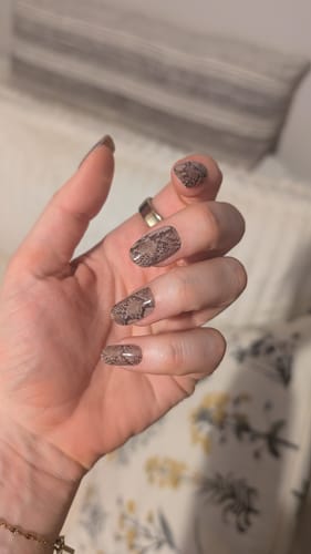 Nahaufnahme der Hand einer Kundin, die die 'Desert Snake' UV Gel-Nagelfolien mit Schlangenmuster trägt.