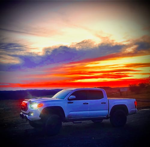 Customer's white truck with a wider stance from the 1" wheel spacers, shown against a vibrant sunset.